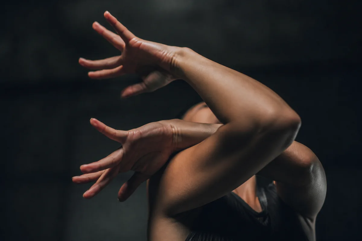 Détail des bras en rotation caractéristique du vocabulaire waacking sous un éclairage contrasté